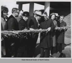 Dignitaries pause before cutting a ceremonial ribbon made of wheat strung across I-94