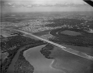 Aerial view, looking NW, of I-94 bridge construction. At the lower left one can see sand traps at Fargo Country Club and the rows of trees at Riverside Cemetery.